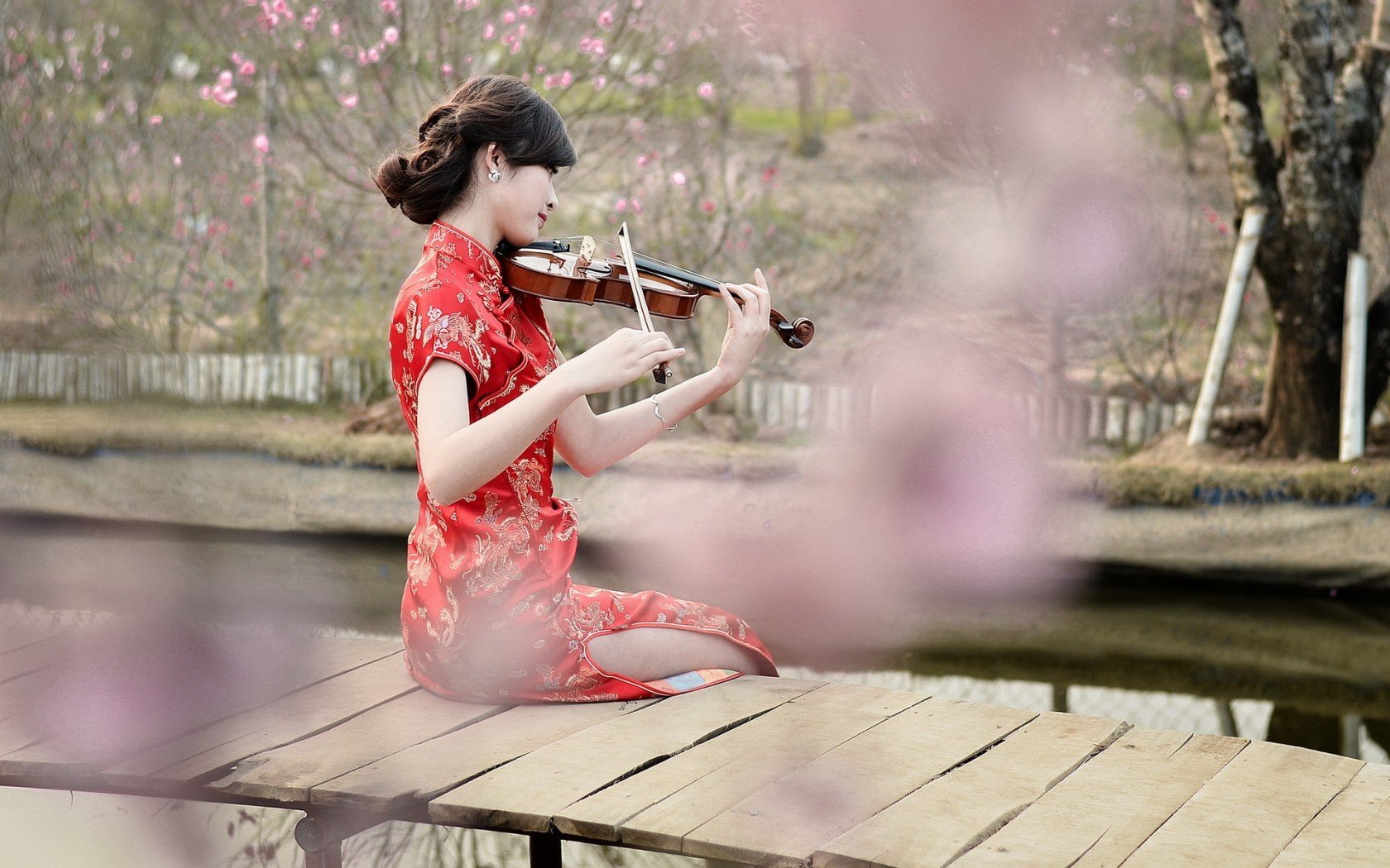 women, Model, Brunette, Long hair, Asian, Women outdoors, Violin, Playing, Sitting, Pier, Wooden surface, River, Trees, Flowers, Red dress Wallpaper