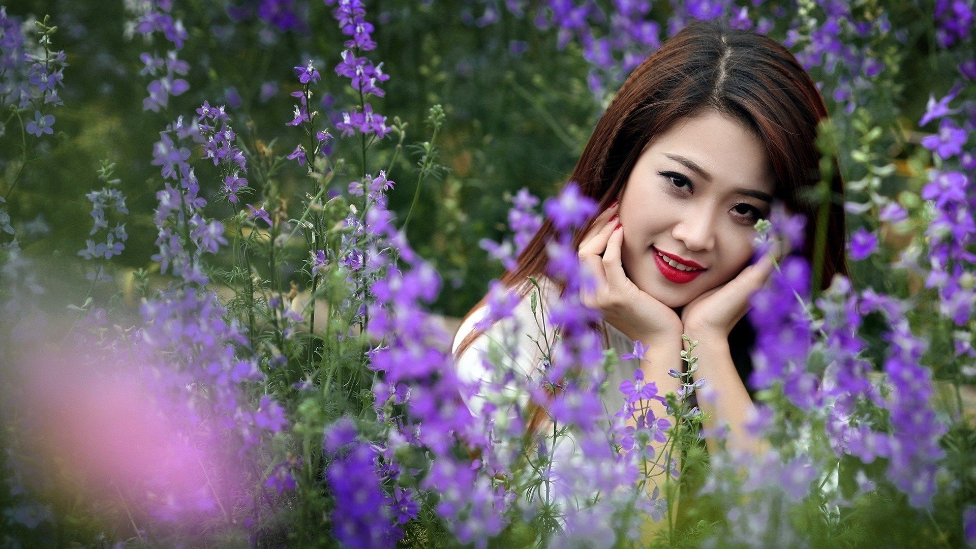 women, Model, Brunette, Long hair, Asian, Women outdoors, Nature, Field, Flowers, Grass, Smiling, Face, Looking at viewer, Depth of field, Red lipstick Wallpaper