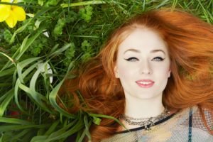 women, Model, Redhead, Long hair, Face, Blue eyes, Red lipstick, Open mouth, Smiling, Sophie Turner, Women outdoors, Lying down, Nature, Grass, Makeup, Yellow flowers